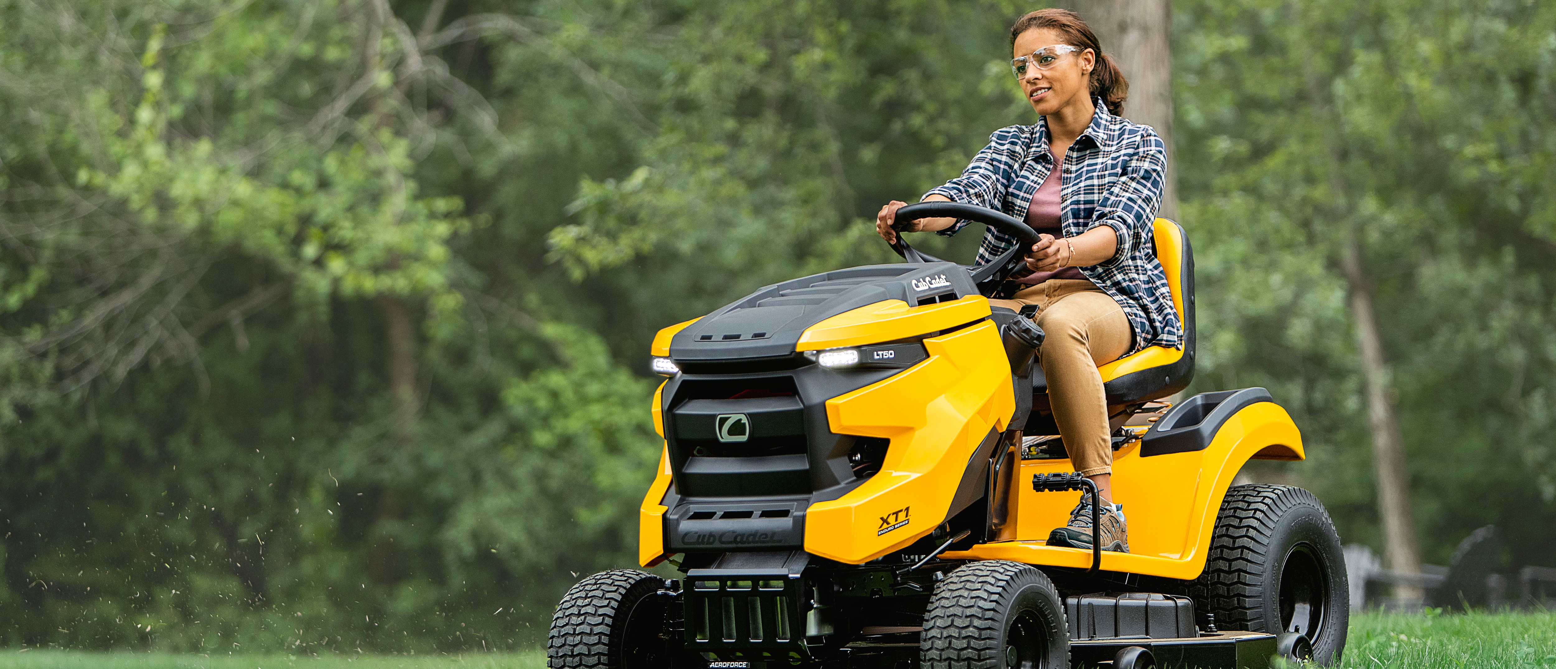 Close up of a woman on a yellow and black Cub Cadet riding lawn mower